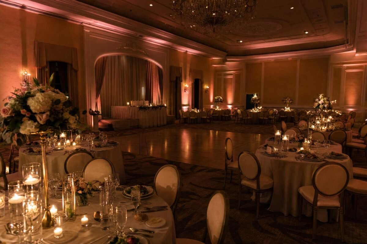 Wedding reception room with warm amber uplighting and pin spot lights on tables